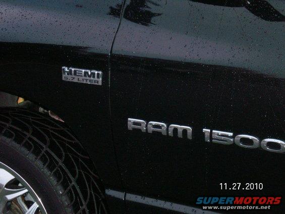 Black Dodge Ram 1500 pickup truck side view, showing HEMI 5.7 LITER badge and RAM 1500 lettering