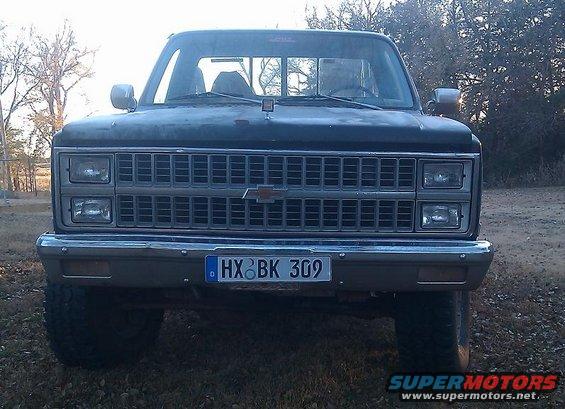 Front view of a dark-colored Chevrolet pickup truck with a chrome grille and license plate HX BK 309