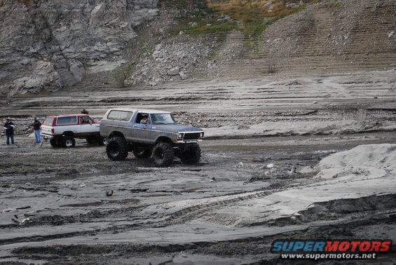 Gray Ford Bronco with large tires driving on a dirt track