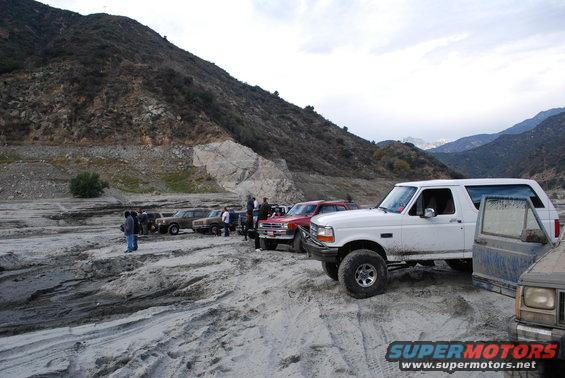 White 1996 Ford Bronco parked in a dry riverbed with other vehicles