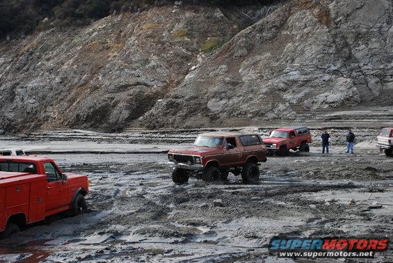 Red 4x4 SUV driving through mud, 1980s model