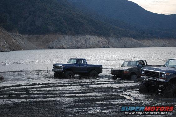 Blue 1979 Ford F-150 stuck in mud with other trucks nearby