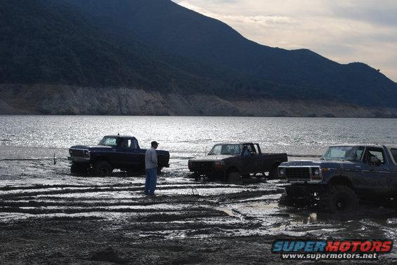 Three trucks stuck in mud, one is a 1979 Ford F-Series