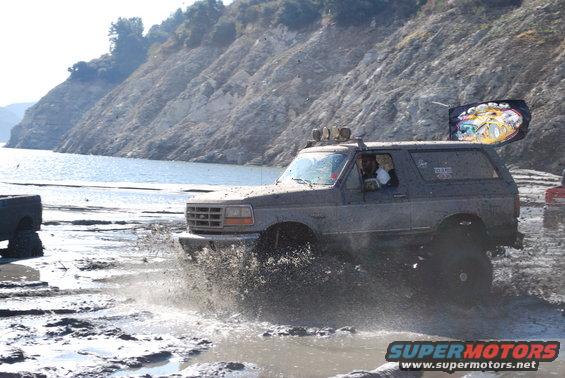 Gray Ford Bronco driving through mud, splashing water