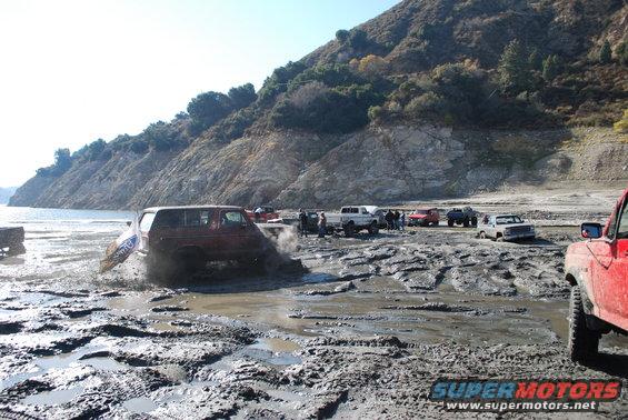 Red SUV stuck in mud with other vehicles in background