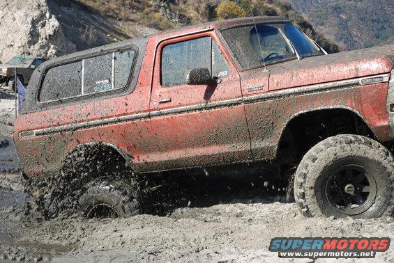 Red SUV stuck in mud, another vehicle visible in background