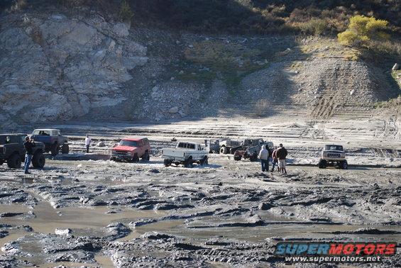 Several off-road vehicles gathered in a muddy, rocky terrain