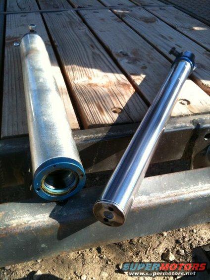 Two shock absorbers, one silver and one chrome, on a wooden surface