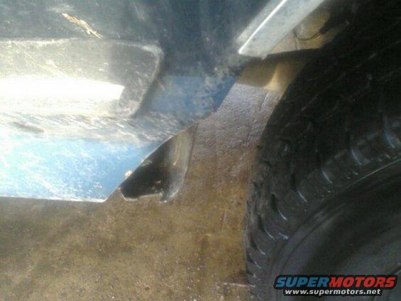Close-up of a vehicle's wheel well and lower fender edge, showing a tire