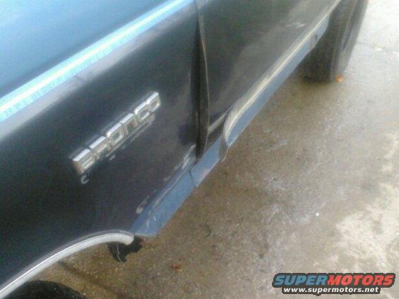 Dark blue vehicle side panel with chrome Bronco emblem and a blue stripe