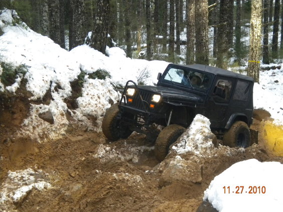 Black Jeep Wrangler navigating a muddy and snowy trail in a forest. The date 11.27.2010 is visible
