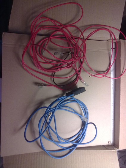 Tangled red and blue wires with connectors, lying on cardboard