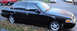 2003 Ford Crown Victoria - A black 2003 Ford Crown Victoria is parked curbside on a street with other vehicles visible in the background.