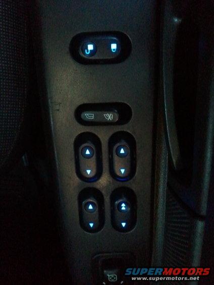 Interior door panel with illuminated power window controls and lock button