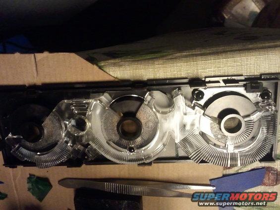 Disassembled instrument cluster with clear plastic housing and metal components