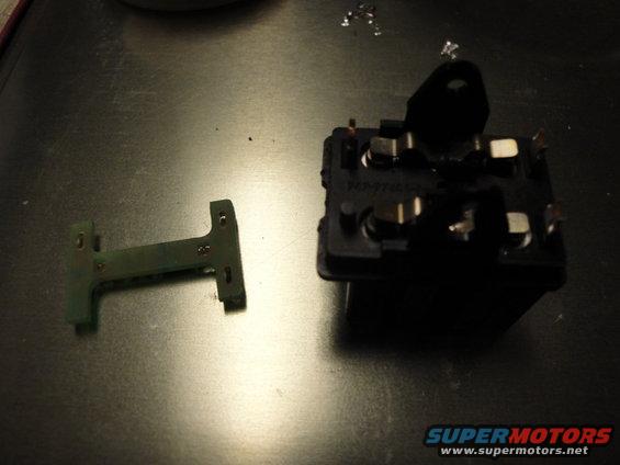 Automotive relay and a small green circuit board component on a dark surface