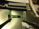 2003 Ford Crown Victoria - A close-up view of a green circuit board with various electronic components, held by two sets of tweezers.