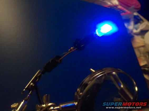 Blue LED light attached to a helping hands stand, with wires visible