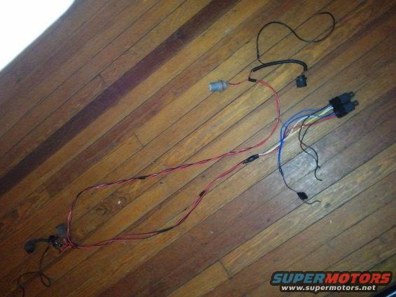 Headlight harness with red, blue, and white wires on a wooden floor