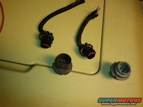 Headlight harness connectors and bulbs on a yellow surface
