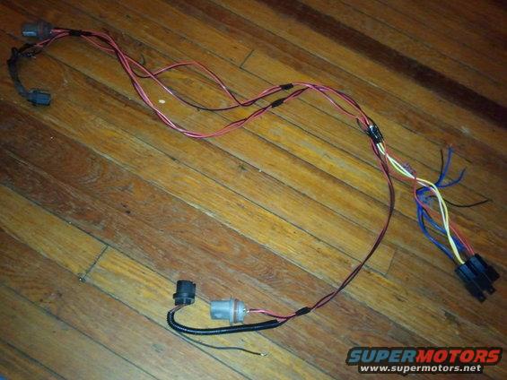 Vehicle wiring harness with multiple connectors and wires, laid out on a wooden floor