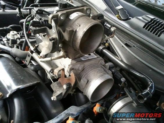 engine throttle body assembly with two connected units and various hoses and wires