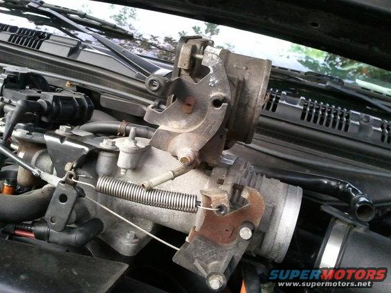 Close-up of a car's throttle body assembly with a spring and cables