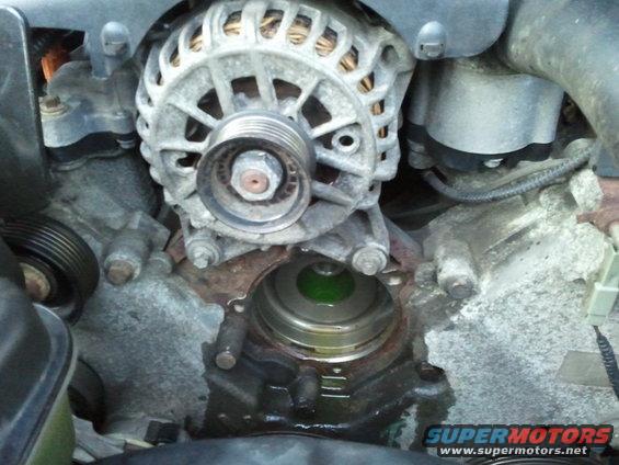 Engine water pump with green coolant visible