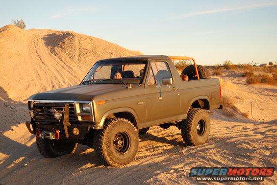 Olive green Ford Bronco with off-road tires parked on a dirt hill