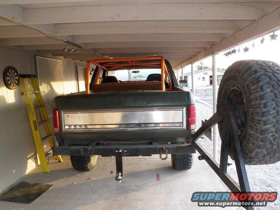 Rear view of dark green SUV with orange roll cage and external spare tire