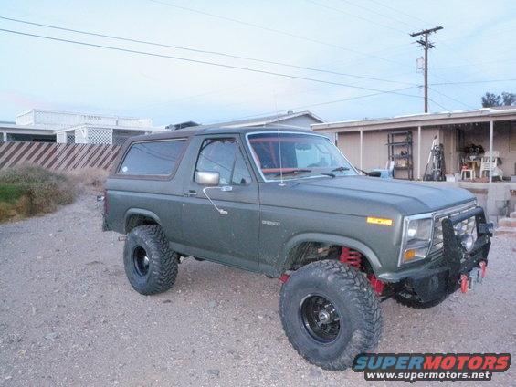 Olive green Ford Bronco with lifted suspension and off-road tires parked on gravel