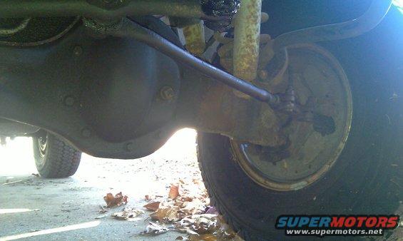 Close-up of a vehicle's rear axle, differential housing, shock absorber, and tire