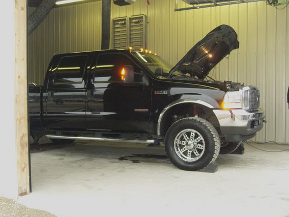 Black pickup truck with hood open, parked inside a garage