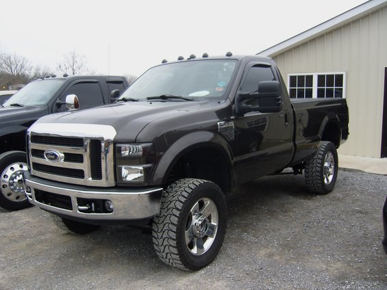 Dark brown Ford F-Series truck, 3/4 front view, lifted with chrome grille