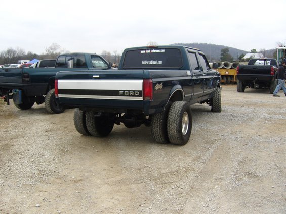 Dark teal Ford F-Series dually truck with a silver stripe on the tailgate, seen from the rear