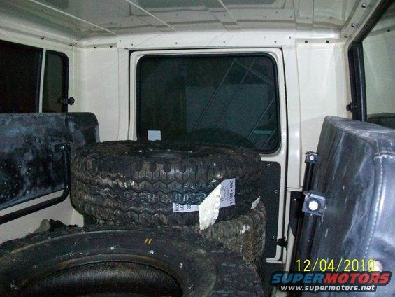 Interior view of a vehicle showing stacked spare tires and seats. Date stamp reads 12/04/2010