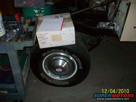 Jeep wheel with Michelin tire and a box on top. Tools and storage bins in background