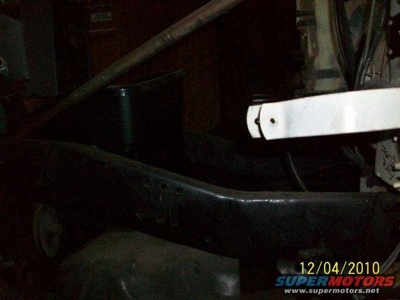 Close-up of a dark metal vehicle frame with some white metal parts and wiring visible. Date stamp reads 12/04/2010