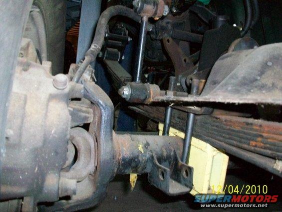 Close-up of front axle, leaf spring, and shock absorber assembly