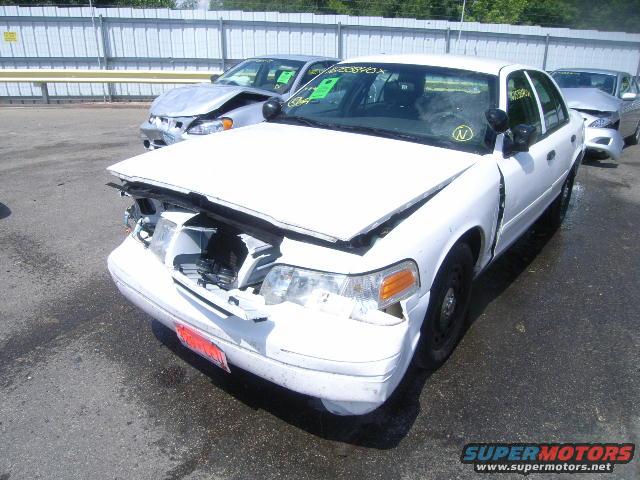 White sedan with front-end damage, hood open. Another damaged car behind it