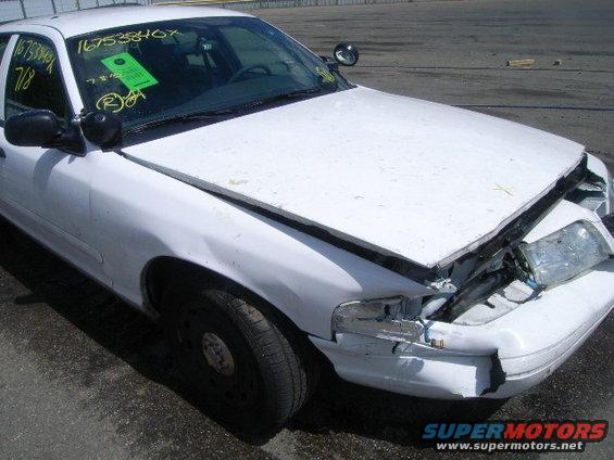 White sedan, front end smashed in, hood up, driver's side mirror intact