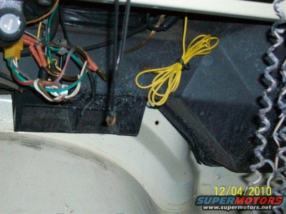 Close-up of a tangled wiring harness with yellow and colored wires, and a black plastic component