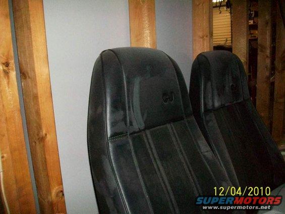 Two black Jeep seats with "CJ" stitched on the headrests. They are in a garage with wooden beams