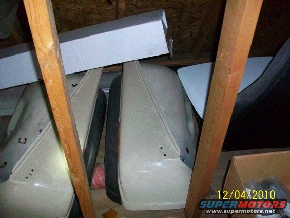 Several car doors and body panels are stacked in an attic, with wooden beams overhead