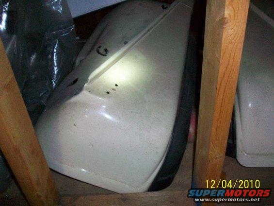 White vehicle fender with black trim and tire, viewed from the side in storage