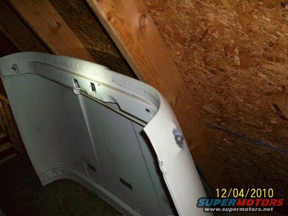 White car hood stored in attic, showing underside and latch mechanism