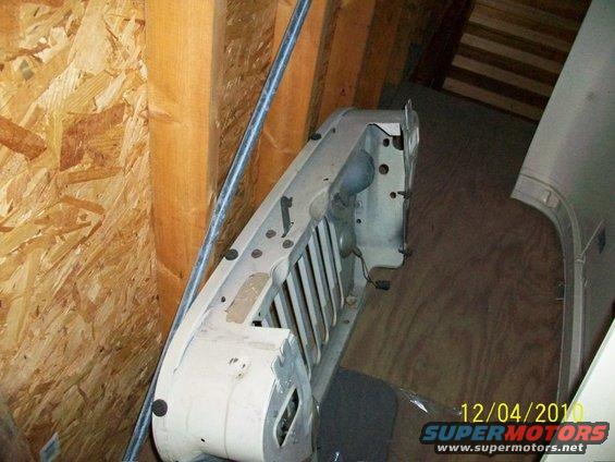 White Jeep grille with vertical slats, seen from the front in an indoor storage area