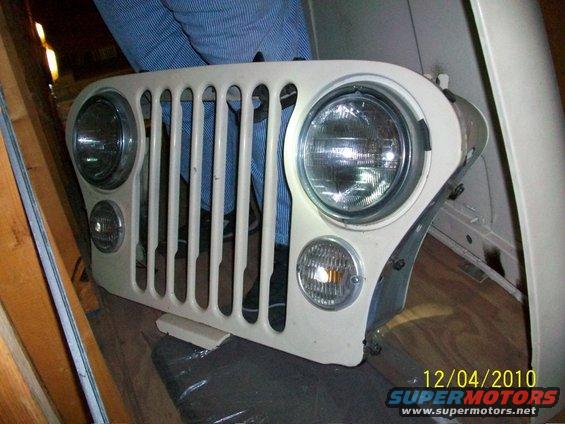 Jeep CJ grille with round headlights and turn signals, held by a person
