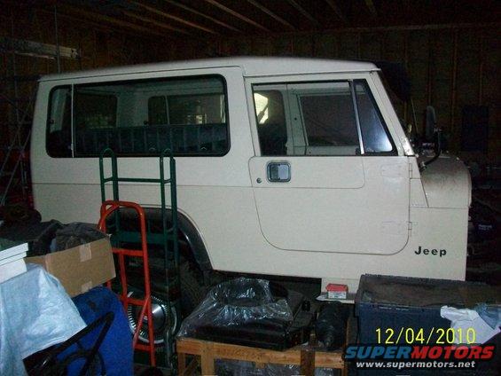 Side view of a white Jeep SUV with a Jeep badge on the rear quarter panel