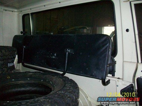 Spare tire and black rear seat inside a white vehicle